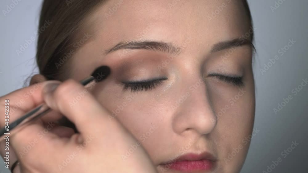 Makeup artist making professional make-up for young woman in beauty studio. Make up Artist uses brush to applies shadow on eyelid Makeup artist making professional make-up for young woman in beauty studio. Make up Artist uses brush to applies shadow on eyelid