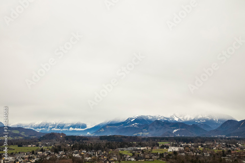 rustic outskirts European city valley with Alps mountain ridge horizon background scenic view in winter time gray sky background © Артём Князь