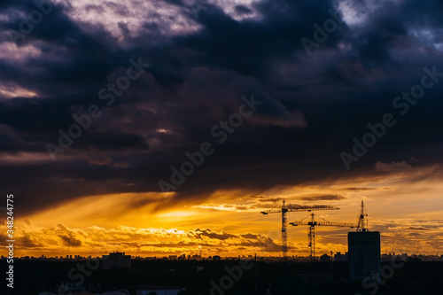 Dramatic sunset over the city covered by clouds over Minsk, Belarus. Tower crane silhouette.