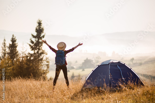 Successful hiking woman silhouette on top of mountains, motivation and inspiration in beautiful sunset view. Female hiker with arms up outstretched on mountain top, inspirational landscape.