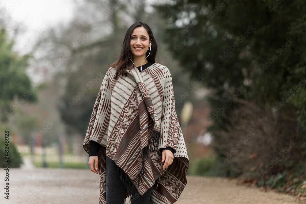 Young Indian woman wearing poncho smiling toothy smile at camera outdoors. Young Indian woman wearing poncho smiling toothy smile at camera outdoors.