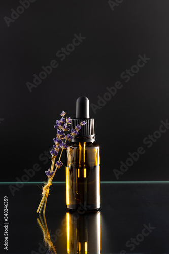 Aromatherapy essential oil dropper bottle and lavender herb flower leaf , black background.
