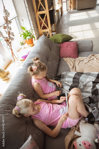 Quiet little girls playing in a bedroom in cute pajamas, home style and comfort. Cute caucasian girls in early morning, sweet dreams. Concept of childhood, happiness, friendship, pajamas party.