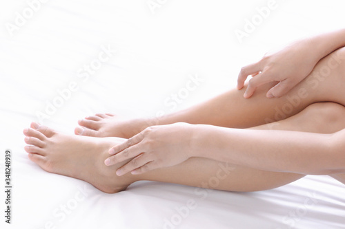 Close up woman touching her leg with pain lying on white bed, health care concept © mraoraor