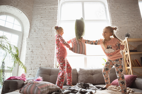 Quiet little girls playing in a bedroom in cute pajamas  home style and comfort. Cute caucasian girls in early morning  sweet dreams. Concept of childhood  happiness  friendship  pajamas party.