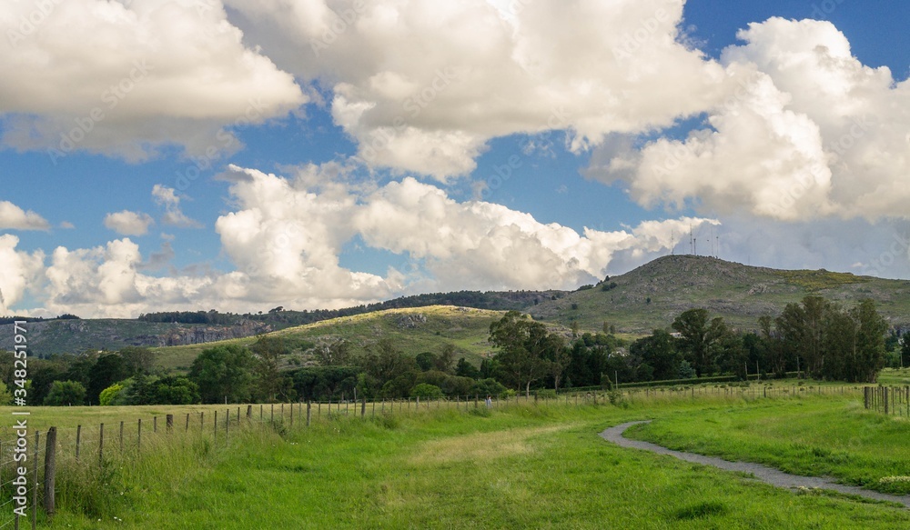 Fototapeta premium PAISAJE SERRANO BAJO UN CIELO CELESTE CON NUBES