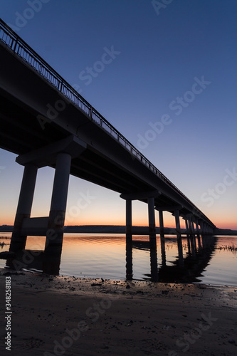 Road bridge over the river at dusk, view from below. Suburban architecture © melnikofd