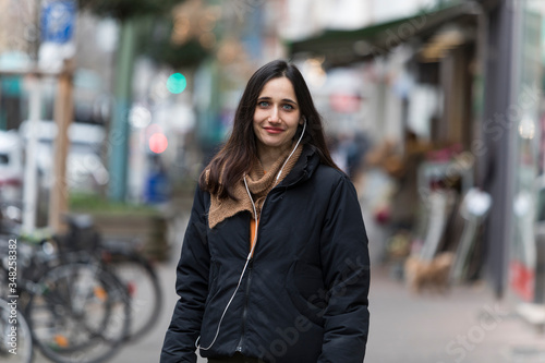 Young Indian woman with sincere smile posing on sidewalk. Front view.