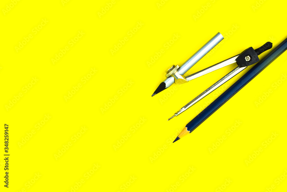 Blue color wood pencil crayon placed beside a silver pencil attached to a compass Blue color wood pencil crayon placed beside a silver pencil attached to a compass