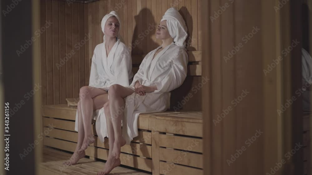 Wide shot of confident young women crossing legs in spa. Beautiful Caucasian ladies resting in luxurious hotel on weekends. Luxury, lifestyle, beauty, body care.