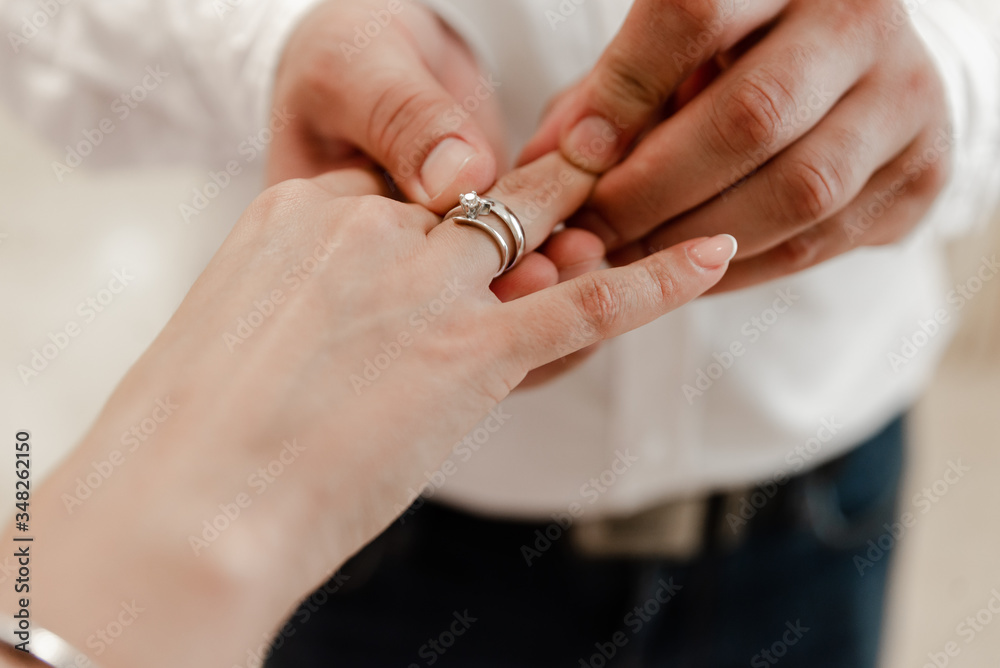 Fototapeta premium The process of how a bride or groom puts on a wedding or wedding ring, bring it, holds his hand, a beautiful bouquet