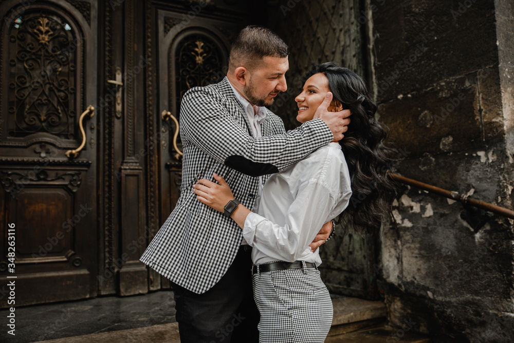 couple in love on the stairs,girl with a guy go down the stairs,stylishly dressed young couple,mature man in a checkered jacket holds hands a girl of European appearance,couple on the background 