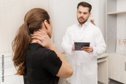 Male doctor examining female patient suffering from neck pain. Medical exam. Chiropractic, osteopathy, post traumatic rehabilitation, sport physical therapy. Alternative medicine, pain relief concept.