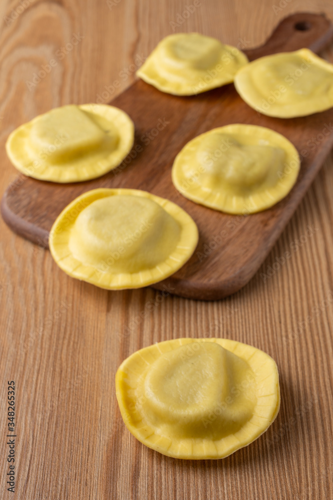 Top view of mushroom ravioli on kitchen table and wooden table, vertical Top view of mushroom ravioli on kitchen table and wooden table, vertical