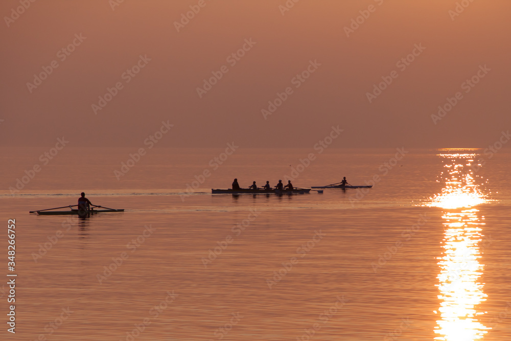Rowing Team Training with Trainer over Shimmering Lake at Sunset