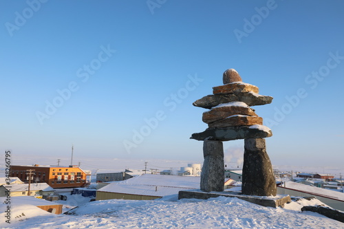 Single Inuksuk or Inukshuk landmark covered in snow on the top of the hill in the community of Rankin Inlet, Nunavut, Canada photo