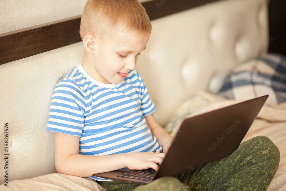 Boy kid sitting on the bed and using a digital tablet laptop notebook. Boy kid sitting on the bed and using a digital tablet laptop notebook.