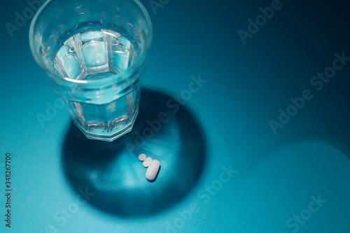 foto horizontal con vaso de agua proyectando sombras y  pastillas  © DondykRiga
