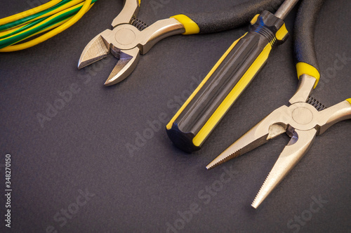 Electrician's tools and wire on black background for repairing energized systems or communications