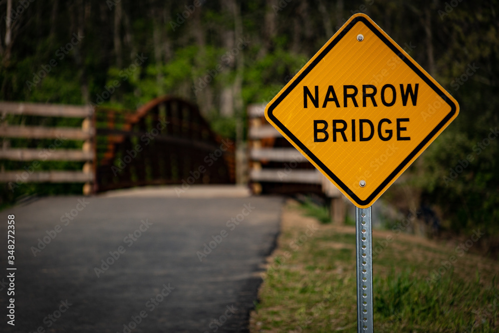 Narrow bridge sign in the park trail