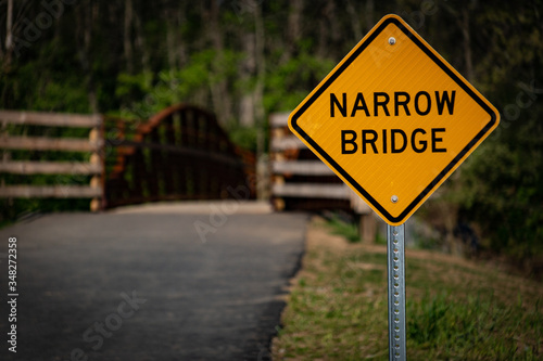 Narrow bridge sign in the park trail