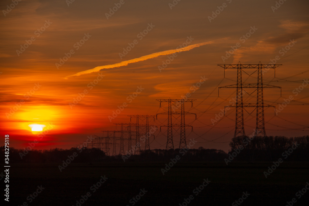 Sunset with power pylons in the skyline and trees background