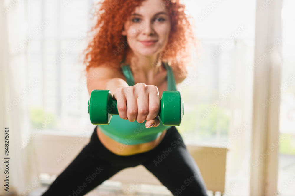 Woman has home sport training with dumpbells