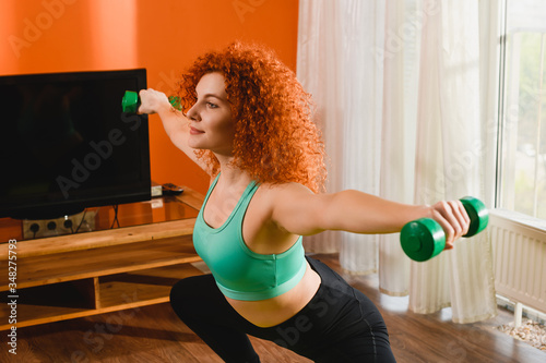 Showy sporty girl home portrait with dumpbells photo