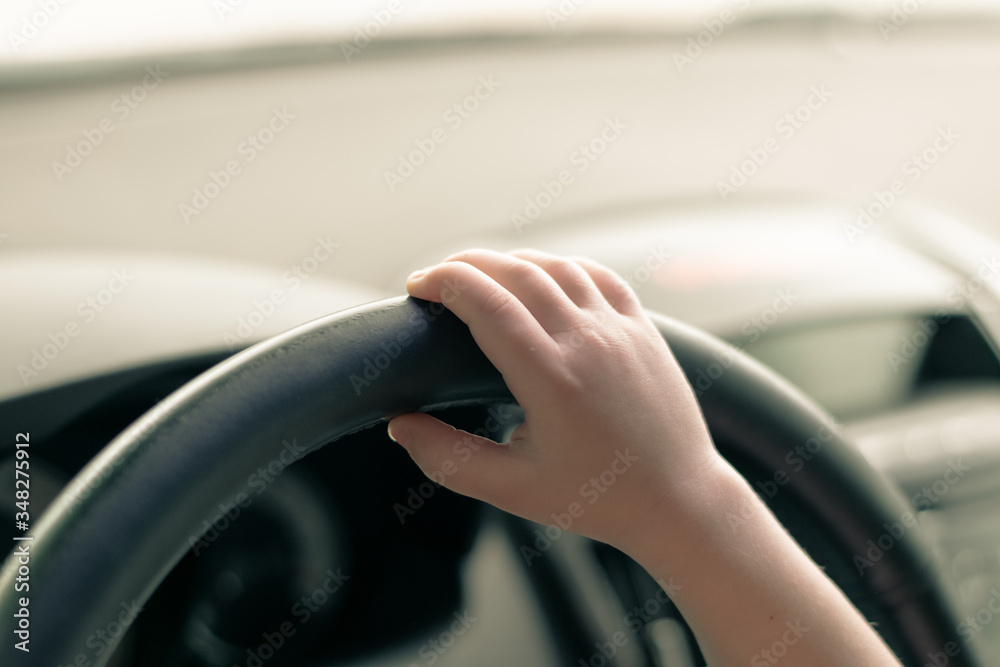 Children's hand on the steering wheel of a car. Boy driving a car