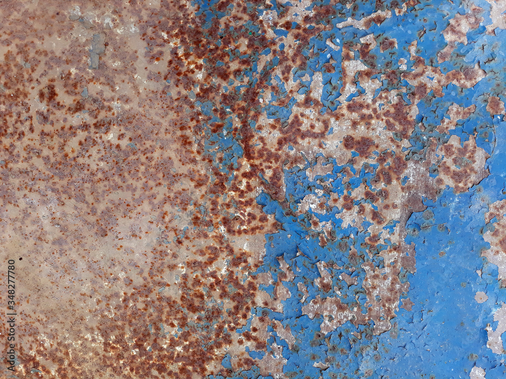 The texture of the old rusty metal sheet is partially covered with peeling blue paint. The texture of the old rusty metal sheet is partially covered with peeling blue paint.
