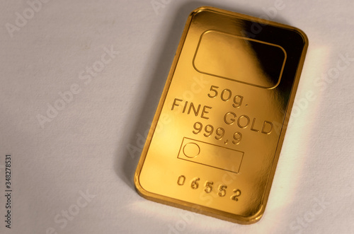 999.9, fineness minted gold bar weighing 50 grams on a gray background.