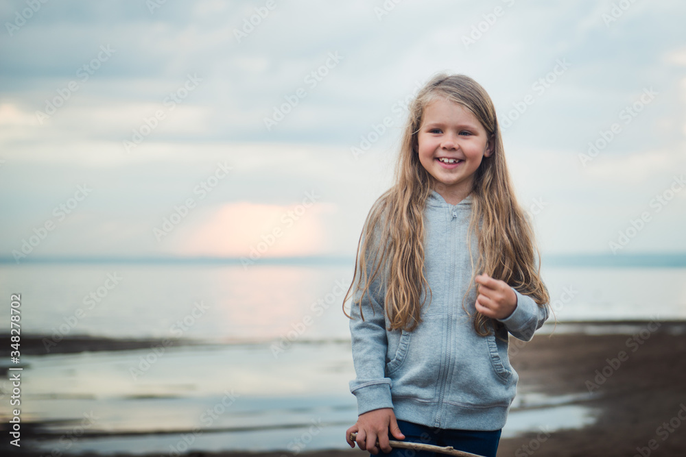 Cute girl portrait outdoors, happy kid walking on the river shore