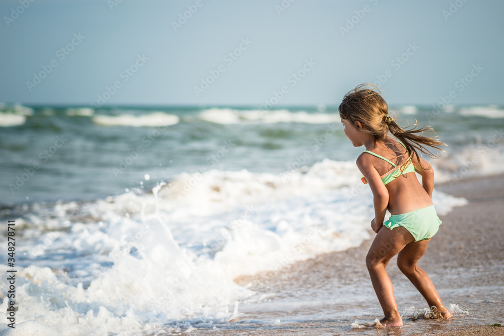 Rear view of a little four year old girl swimming in the sea on a warm summer day during summer vacation in a tropical country. Concept vacation with children. Rear view of a little four year old girl swimming in the sea on a warm summer day during summer vacation in a tropical country. Concept vacation with children.