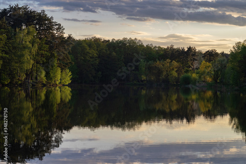 Beautiful sunset on the lake with reflection in the water surface. Lake in the forest.