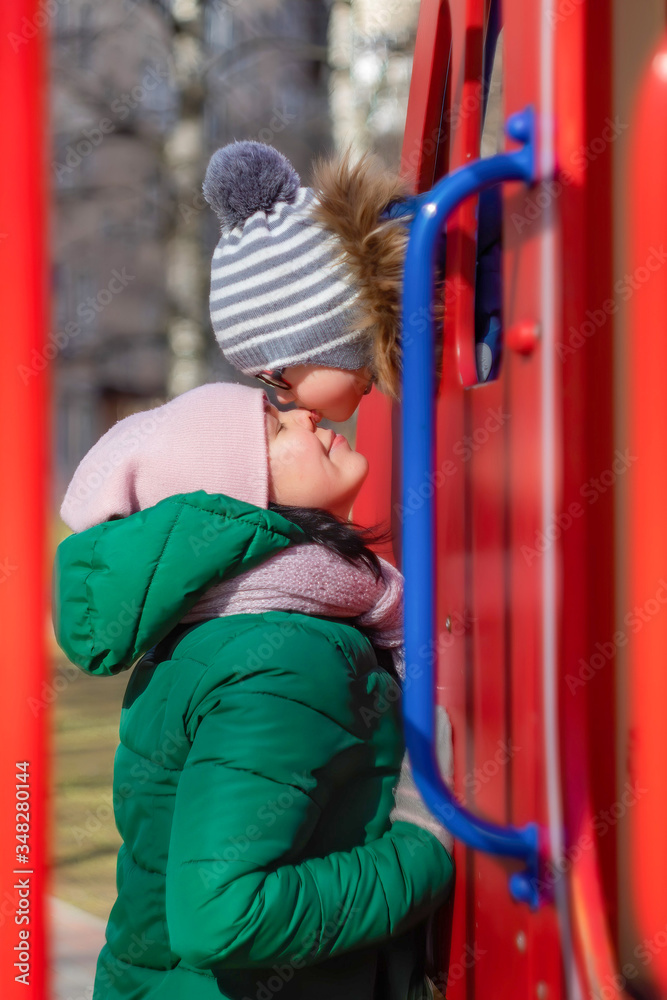Fototapeta premium Little son kisses mom in the nose at the playground