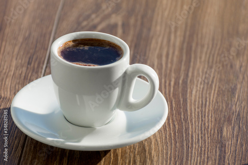 A cup of black coffee is on the table in the early morning.