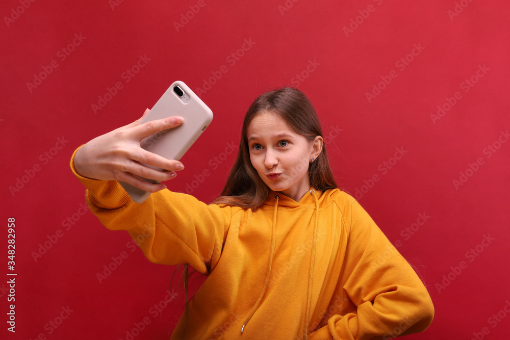 A beautiful young girl takes a selfie on her cell phone. A beautiful young girl takes a selfie on her cell phone.