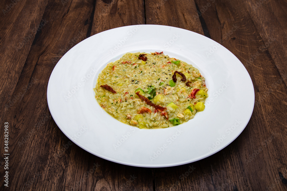 Italian risotto with king crab in a white plate on a wooden table. Italian risotto with king crab in a white plate on a wooden table.