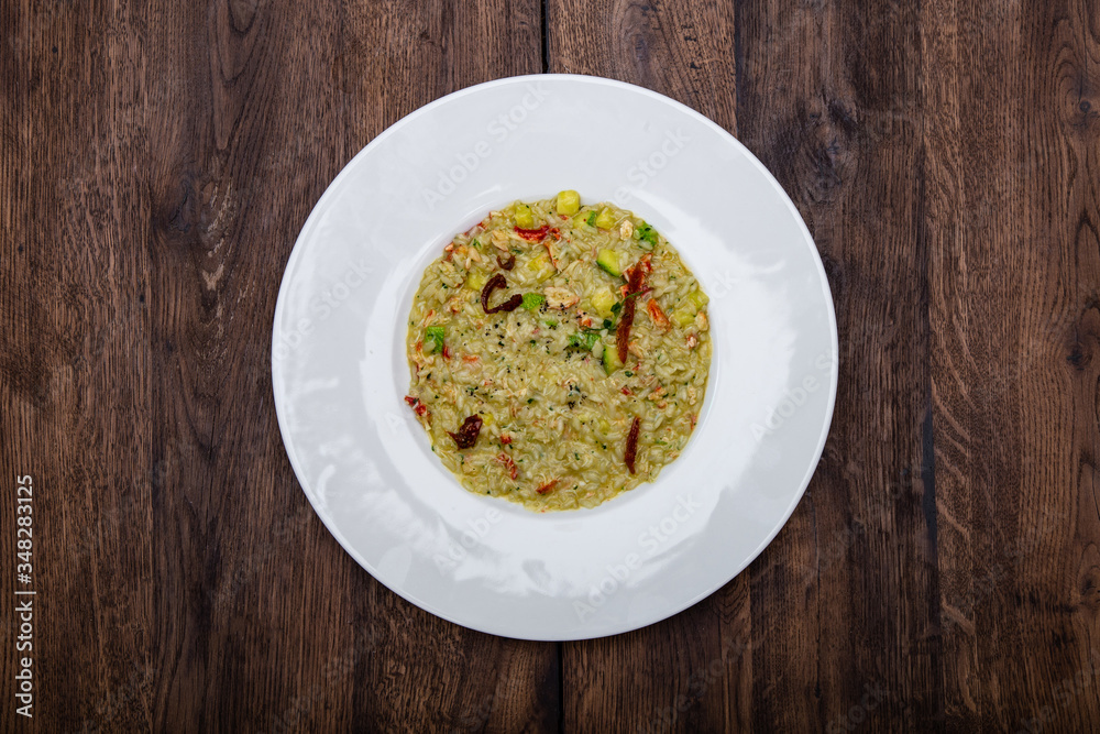 Italian risotto with king crab  in a white plate on a wooden table.