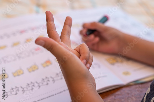 Fotografija Child's hand doing math while counting on fingers
Boy doing homework learning t