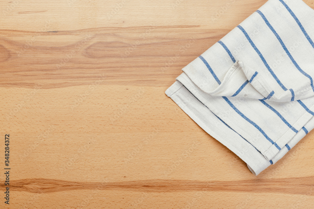 Top view on a wooden table with a linen kitchen towel or textile napkin.