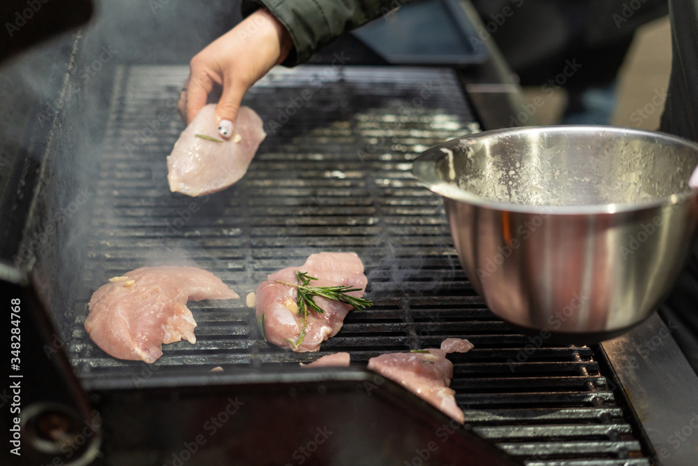Woman putting pieces of turkey with rosemary onto a grill pan