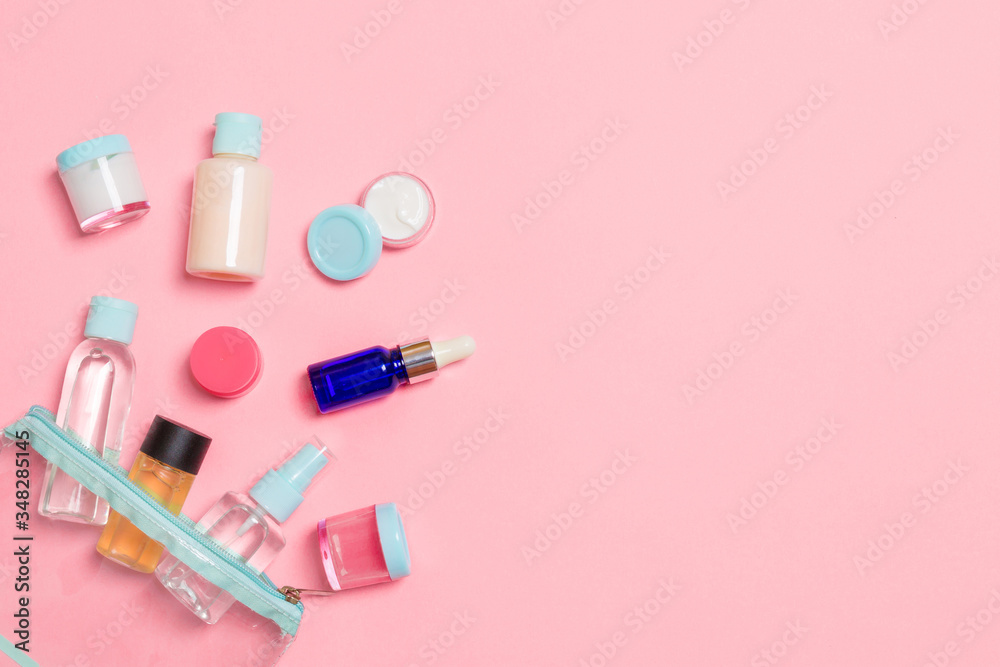 Group of small bottles for travelling on pink background. Copy space for your ideas. Flat lay composition of cosmetic products. Top view of cream containers with cotton pads Group of small bottles for travelling on pink background. Copy space for your ideas. Flat lay composition of cosmetic products. Top view of cream containers with cotton pads