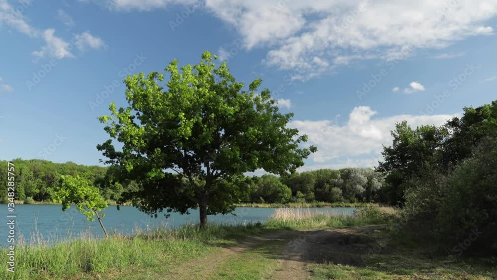 Time lapse of moving clouds over spring landscape near Vysoka pri Morave town in Slovakia. Oak tree with green leaves and country road in foreground. Time lapse of moving clouds over spring landscape near Vysoka pri Morave town in Slovakia. Oak tree with green leaves and country road in foreground.