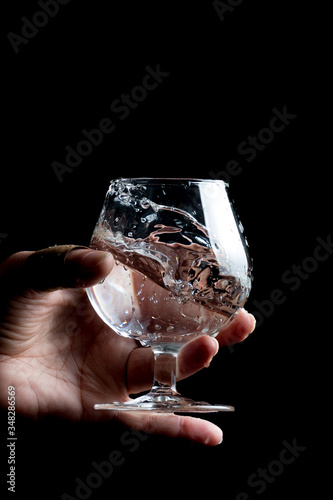splashing water, cognac glass on a black background