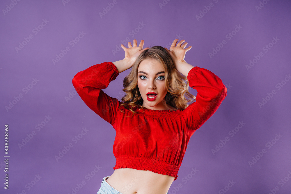 A young beautiful girl shows emotions and smiles in the Studio on a purple background. Girls for advertising A young beautiful girl shows emotions and smiles in the Studio on a purple background. Girls for advertising