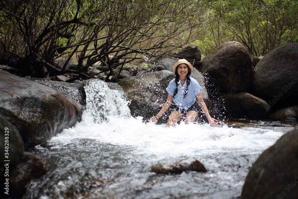 Fototapeta premium Woman soaking in the Trok Nong waterfall in Chanthaburi, Thailand