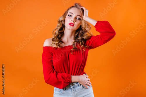 A young beautiful girl shows emotions and smiles in the Studio on an orange background. Girls for advertising