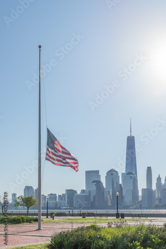 New York City skyline with American flag flying at half-mast in the foreground.