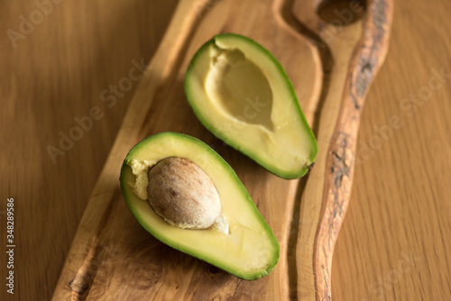 Two halves of avocado on an olive board